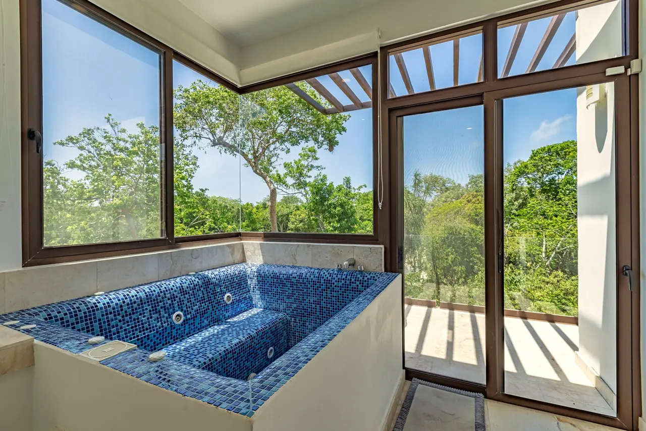 Jacuzzi interior con mosaico azul frente a los ventanales